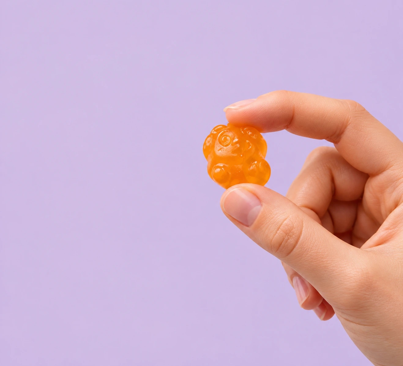 Nærbilde av en hånd som holder en oransje gummy